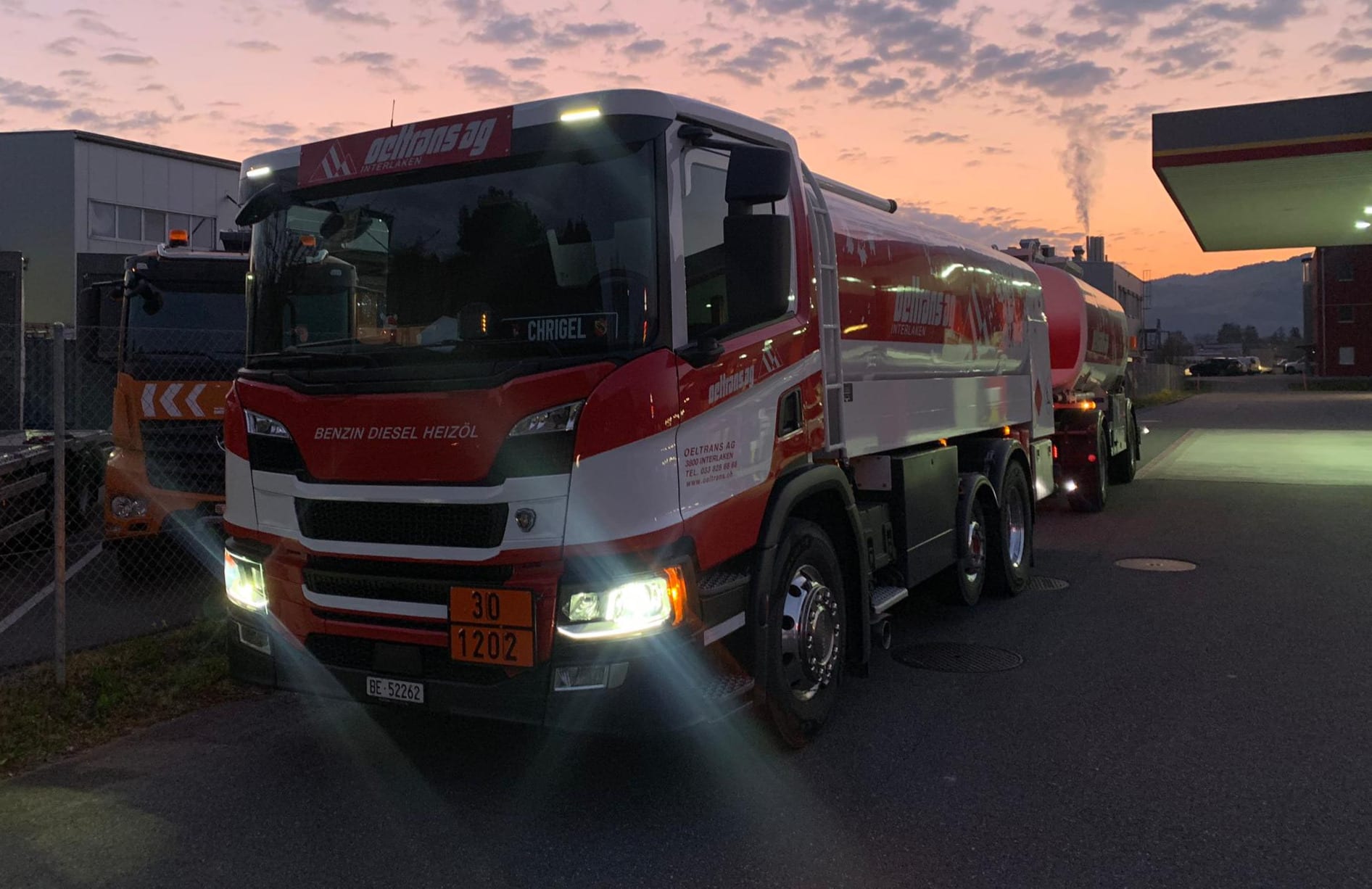 oeltrans Tankwagen mit eingeschalteten Scheinwerfern in der Morgendämmerung